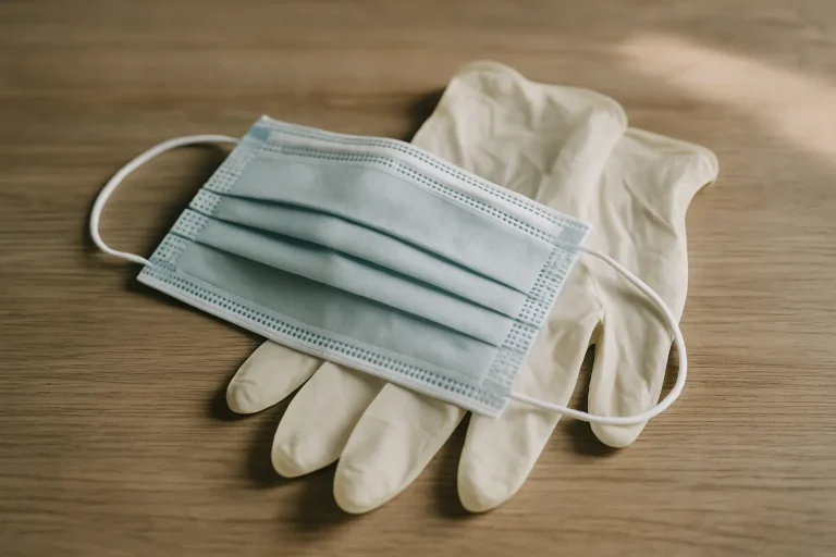 Masque de protection et gants en caoutchouc posés sur une table en bois.